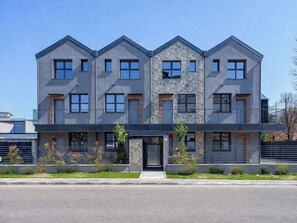 Ein modernes, mehrgeschossiges Gebäude mit einer symmetrischen Fassade, großen Fenstern und einem zentralen Eingang.