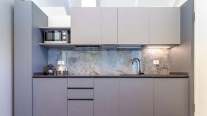 A modern kitchen with grey cabinets, a microwave, a sink, and a marble backsplash. - Flower Residence - Appartamento Lavanda (Lissone)