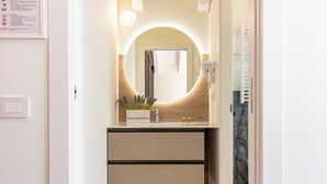 A modern bathroom with a round mirror, a sink, and a towel rack. - Flower Residence - Appartamento Narciso (Lissone)