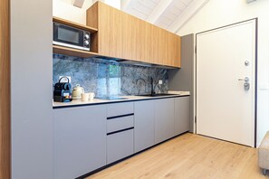 Eine moderne Küche mit Mikrowelle, Holzschränken, einer Marmor-Spritzschutzwand und einer Tür rechts.