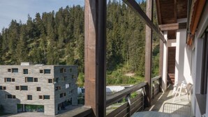 Een balkon met uitzicht op een bebost gebied en een modern gebouw.