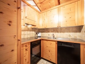 Une cuisine avec des meubles de rangement en bois, un lave-vaisselle et un four.