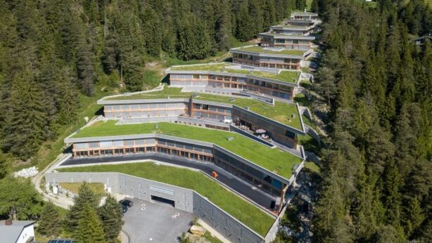A row of modern buildings with flat roofs, surrounded by dense forest. - Residenz Cuolm Liung 52 by Interhome (Laax)