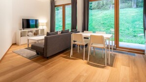 A modern living room with a sofa, TV, and dining area. - Residenz Cuolm Liung 52 by Interhome (Laax)
