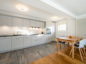 Eine moderne Küche mit weißen Schränken, einem Holzespeisetisch und einem Fenster mit Jalousien.