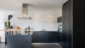 Una cocina moderna con armarios oscuros, una isla central y una estufa integrada.