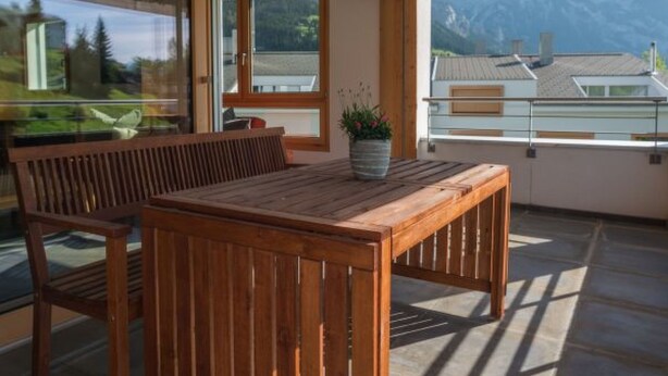 Mesa y banco de madera en un balcón con vista a la montaña.