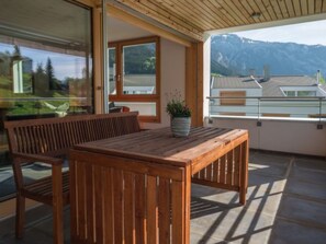 A wooden table and bench on a balcony with a mountain view. - Prada Biala by Interhome (Flims)