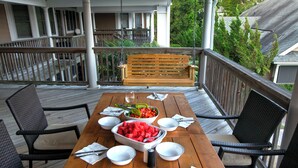 A wooden deck with a dining table set for four, surrounded by wicker chairs. - Bliss: Shared Pool & Sports Center | Short Walk to Beach (Corolla)