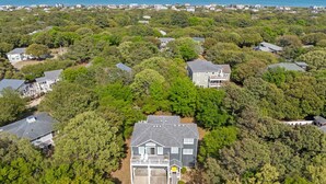 Et boligområde med huse omgivet af frodig vegetation og udsigt til havet.