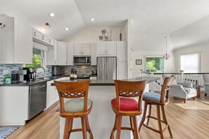 A modern kitchen with white cabinets, stainless steel appliances, and a central island with bar stools.