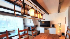 A modern living room with a wooden dining table, chairs, a TV, and a sofa. - Via Sulten 12 by Interhome (Flims)