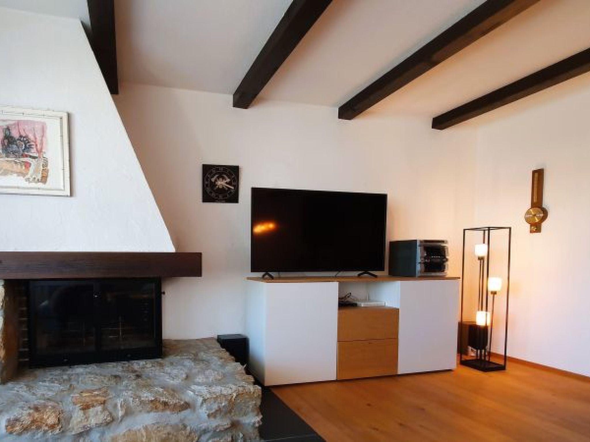 A modern living room with a stone fireplace, a flat-screen TV, and a minimalist design.