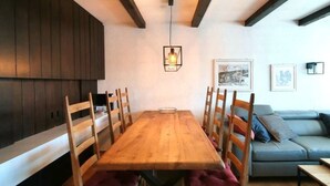 A dining area with a wooden table and chairs, a sofa, and a hanging light fixture. - Via Sulten 12 by Interhome (Flims)