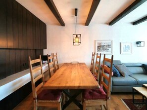 A dining area with a wooden table and chairs, a sofa, and a hanging light fixture. - Via Sulten 12 by Interhome (Flims)