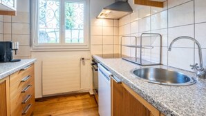 Una cocina con ventana, pileta de acero inoxidable y muebles de madera.