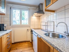 A kitchen with a window, stainless steel sink, and wooden cabinets. - Casa Gronda 2 by Interhome (Laax)