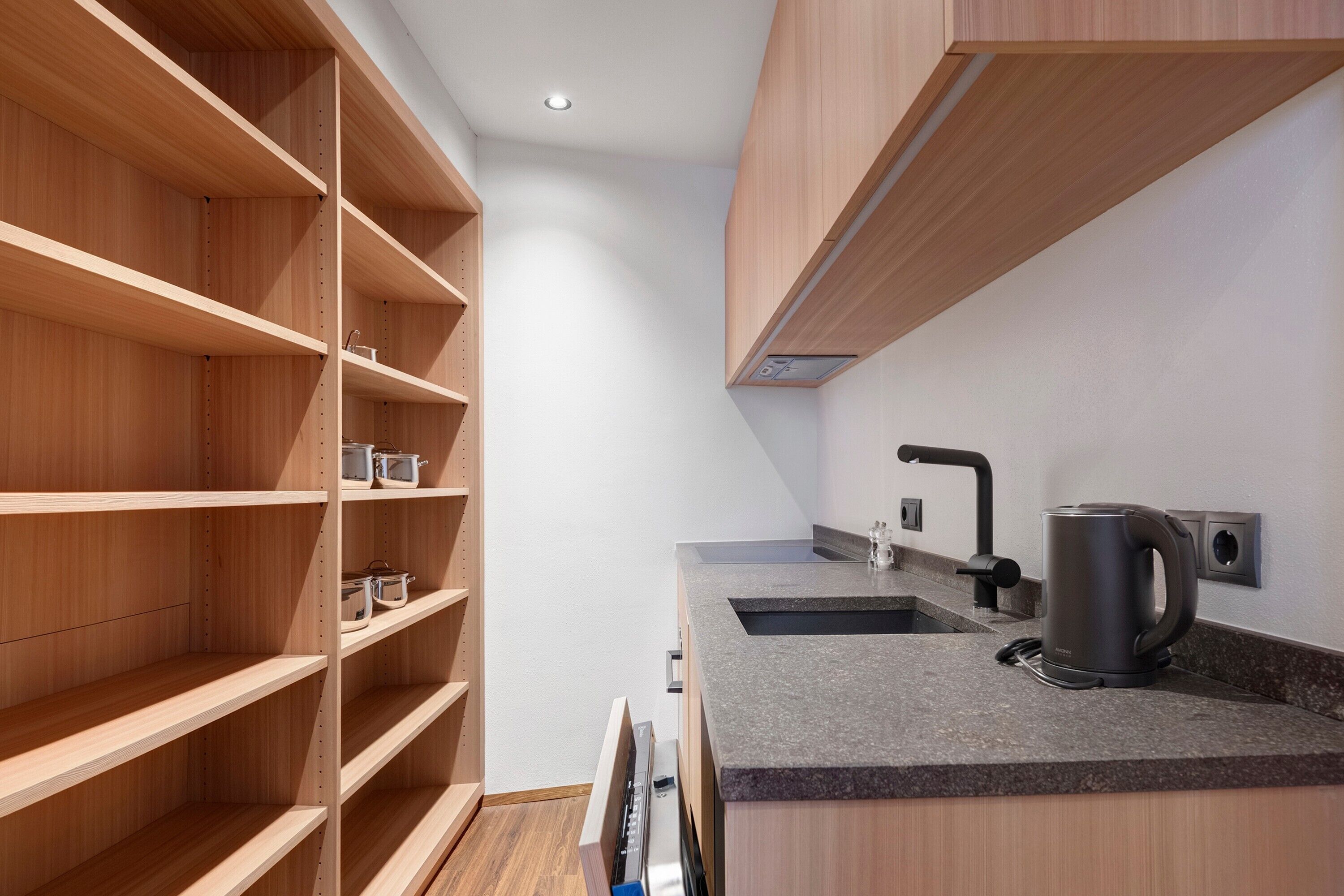 Een moderne keuken met houten kastjes, een granieten aanrecht, een waterkoker en een koffieapparaat.