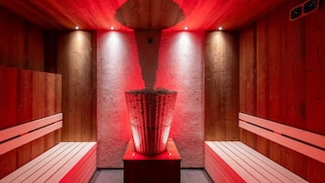 A sauna room with wooden walls, benches, and a central light fixture.