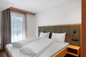 A hotel room with a bed, a nightstand, and a window with curtains. - Apartment 'Smart 5' with Balcony and Breakfast Included - new 2026 (Trodena nel Parco naturale)