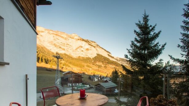 Un balcón con una mesa redonda y dos sillas, con vista a un paisaje montañoso.