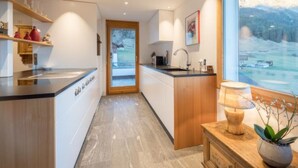 Una cocina moderna con una isla grande, armarios de madera y vistas a un paisaje montañoso.