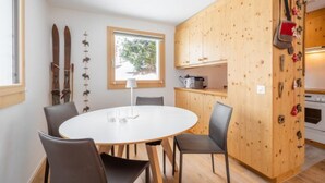 A compact kitchen with a round table, chairs, wooden cabinets, and a window. - Casa Collina 5i-02 by Interhome (Flims)