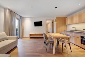 Un salon moderne comprenant un canapé, une table à manger, des chaises et un téléviseur.
