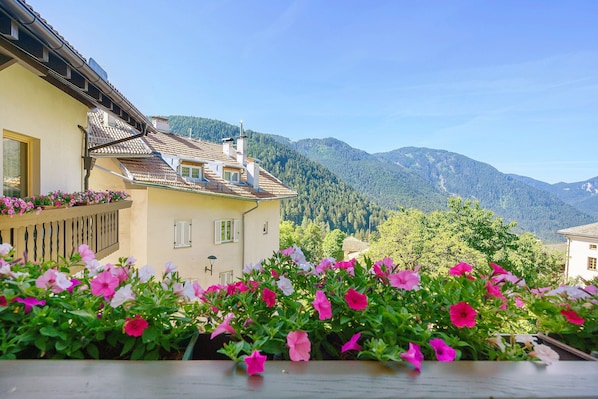 Ein Gebäude mit einem Ziegeldach, einem Balkon voller Blumen und einer Bergkulisse.