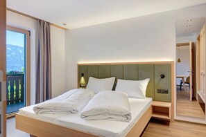 A hotel room with a bed, a nightstand, a lamp, and a view of the outdoors.