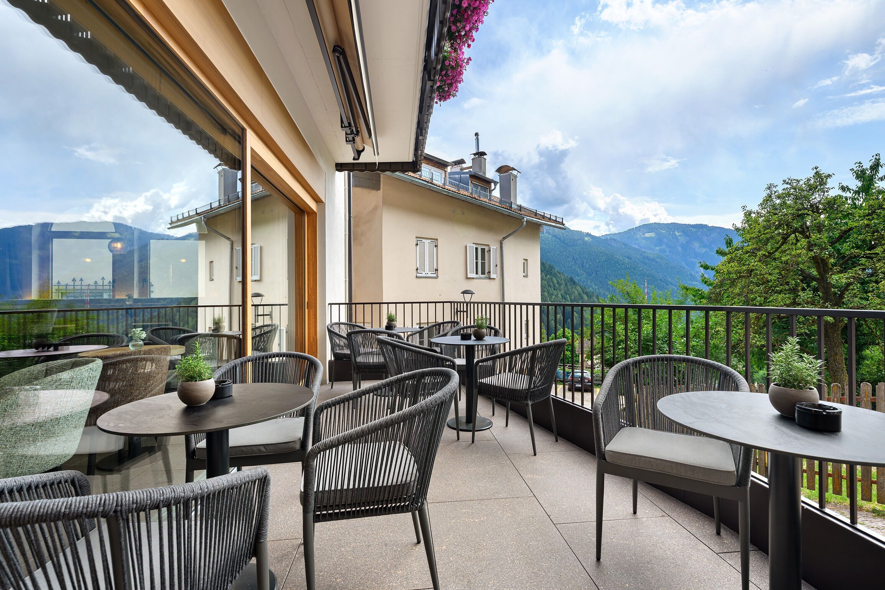 Una terrazza con posti a sedere all'aperto, vista sulle montagne e un edificio con un balcone.