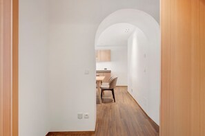 Ein Flur, der in einen Essbereich mit Holzboden und weißen Wänden führt.