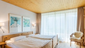 Una stanza con due letti di legno, una sedia e un'opera d'arte appesa al muro.