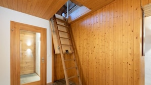 Un interno in legno con una scala appoggiata a una parete, una porta e un pavimento in pietra.