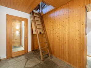A wooden interior with a ladder against a wall, a door, and a stone floor. - Panorama Salums by Interhome (Laax)