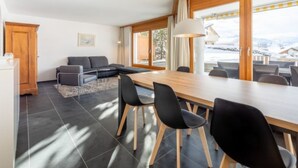 Ein modernes Interieur mit Essbereich, einer Couch und Blick ins Freie.