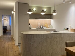 Eine moderne Küche mit Kochinsel, Pendelleuchten und Blick in den Essbereich.