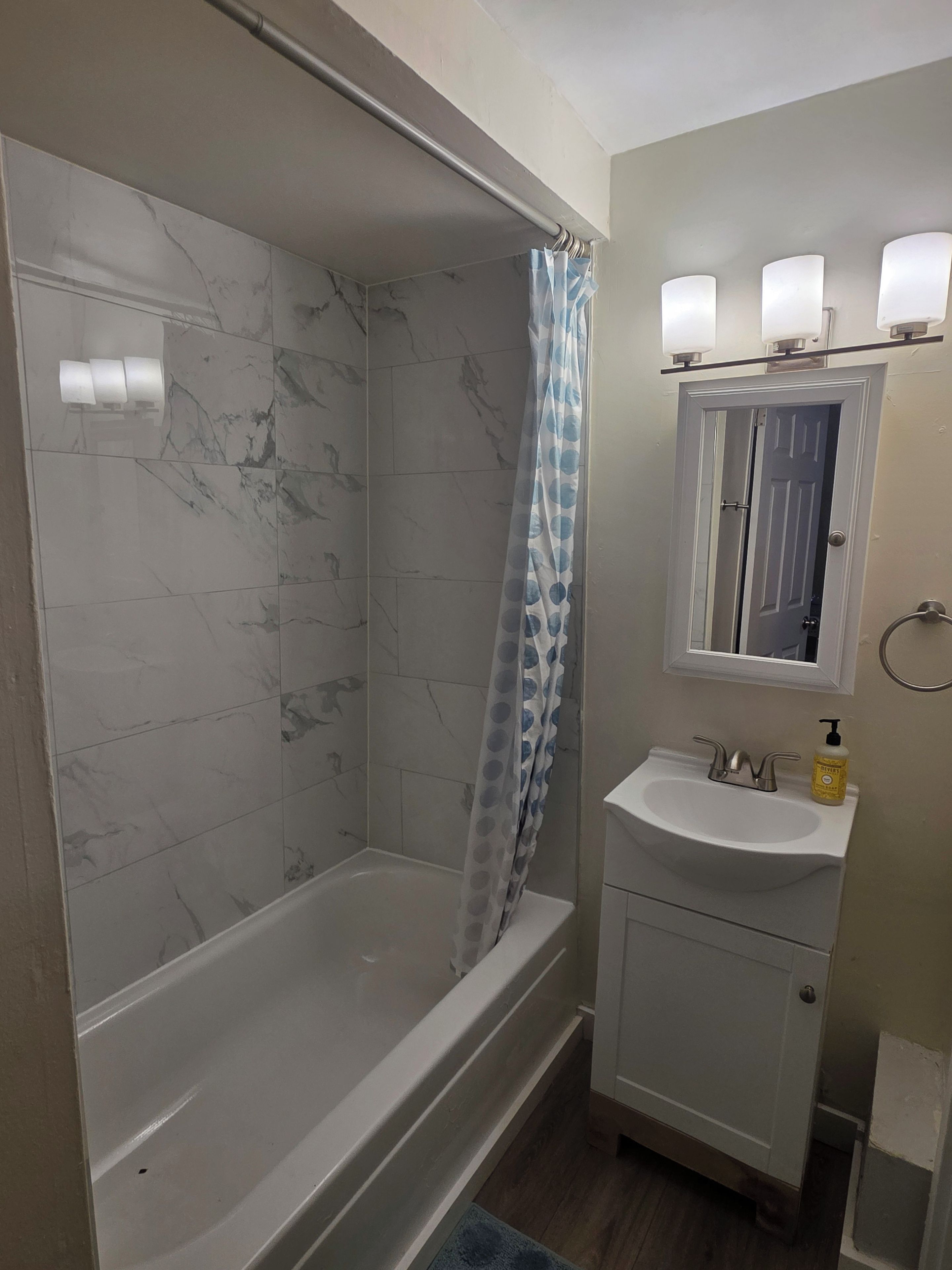 Un baño con bañera, cortina de ducha, lavamanos, espejo y retrete.