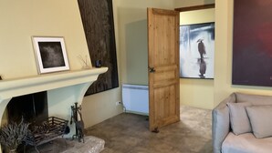 A living room with a fireplace, a wooden door, and a painting on the wall. - Vacation home  by Interhome (Carces)