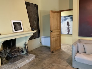 A living room with a fireplace, a wooden door, and a painting on the wall. - Vacation home  by Interhome (Carces)