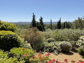 A garden with various plants and trees, a gravel path, and a view of distant hills. - Arts & Flores by Interhome (Carces)