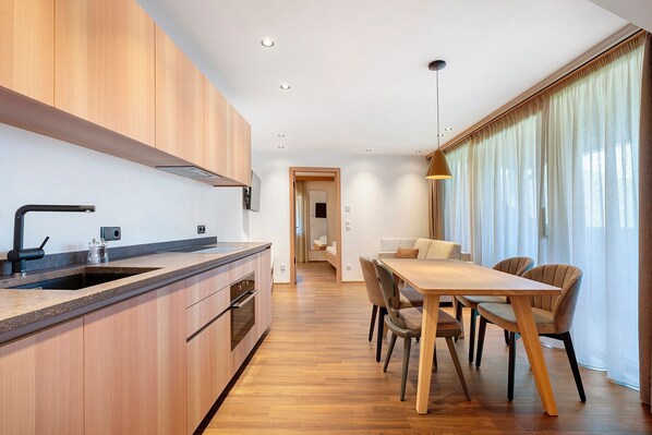 Una cocina moderna con armarios de madera, horno empotrado y una isla grande con pileta.