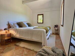 Quarto com cama, mesas de cabeceira, tapete e janela.