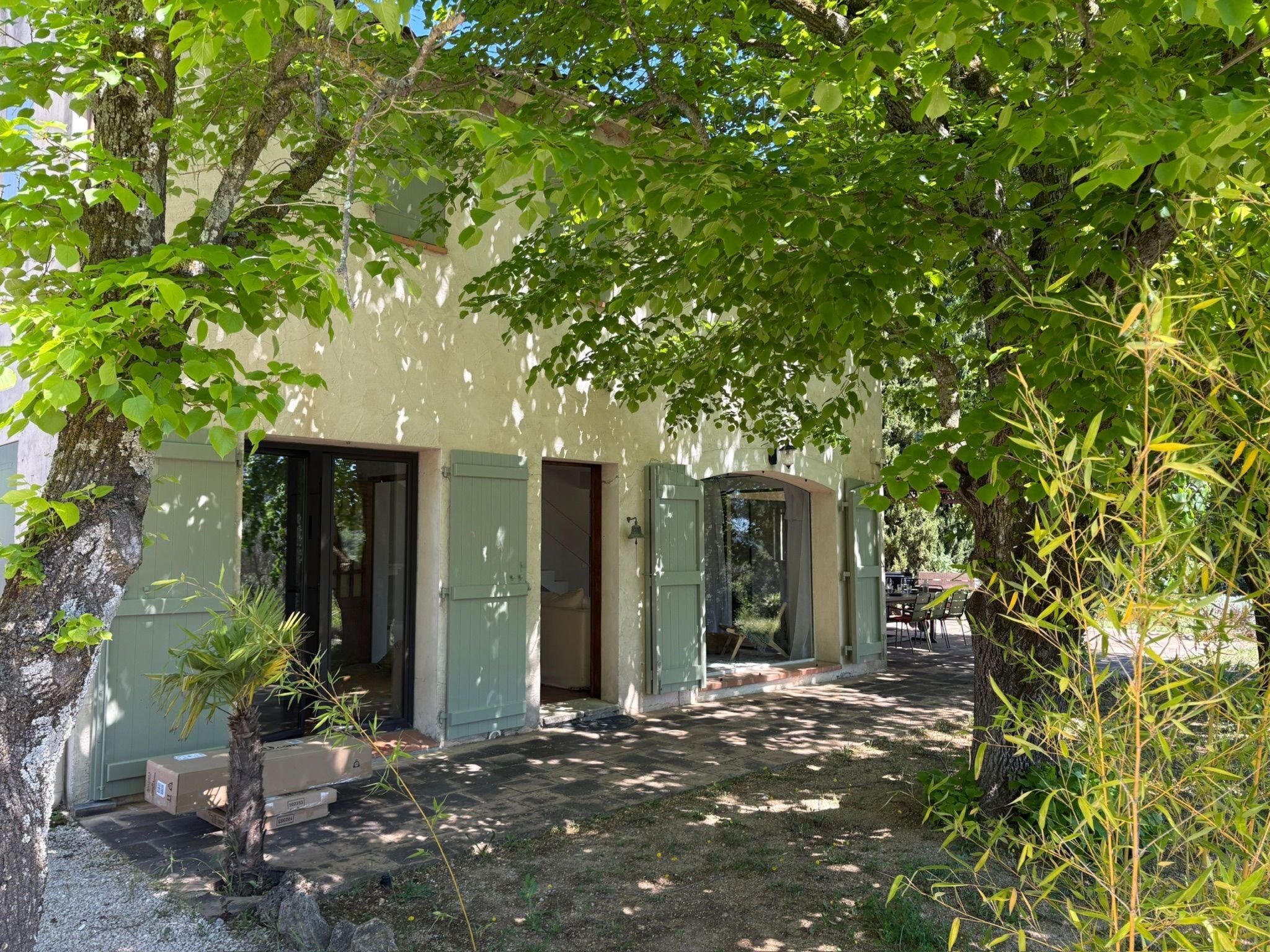 Un bâtiment doté de nombreuses portes et fenêtres, entouré d’arbres et de verdure.