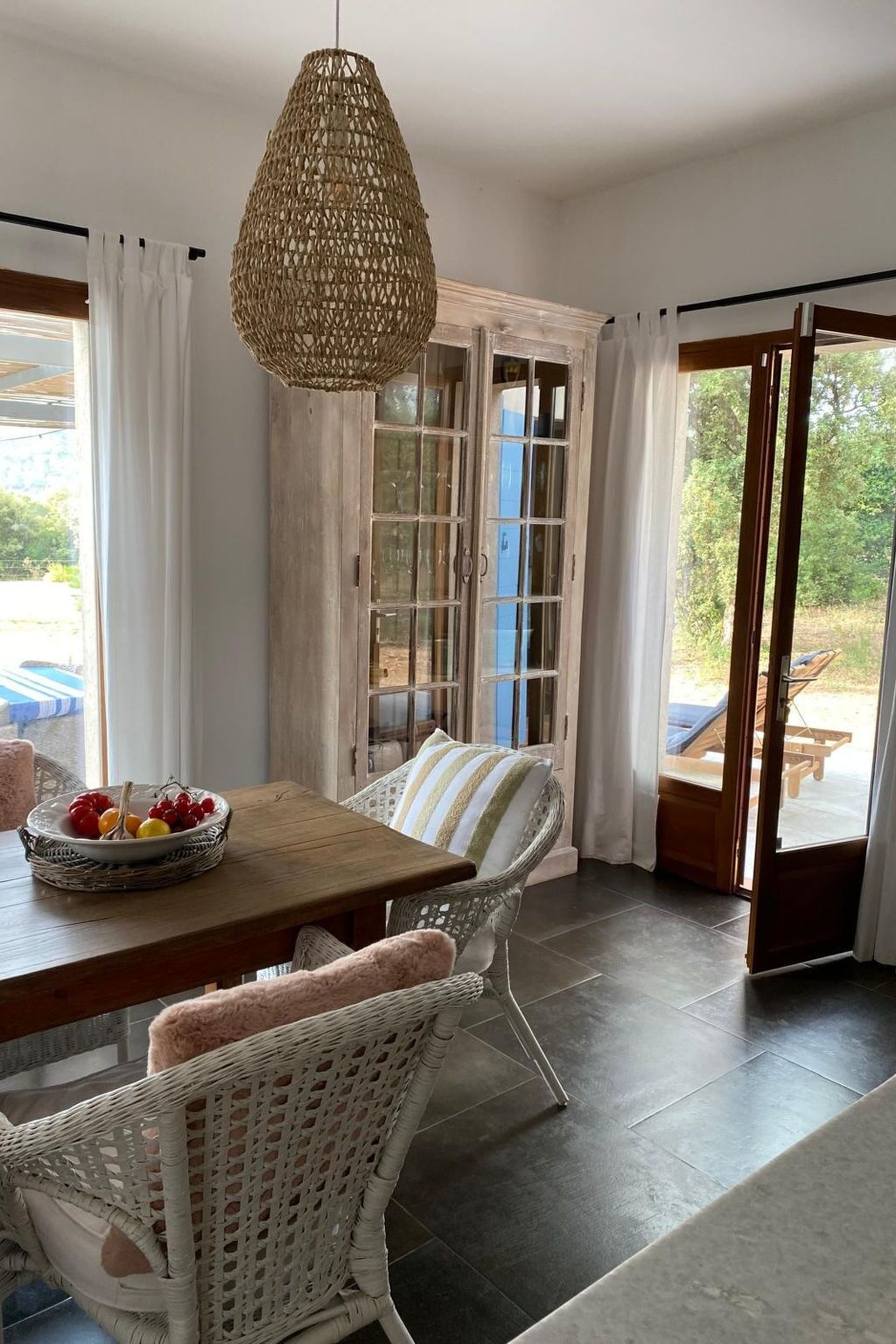 A dining area with a table, chairs, and a hanging light fixture.