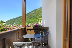 A balcony with a table and chairs, a wooden railing, and a view of a green hillside. - Apartment 'Classic 6' with Balcony and Breakfast Included - new 2026 (Trodena nel Parco naturale)