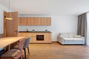 A modern kitchen with wooden cabinets, a dining table, and chairs. - Goldener Adler Apartment Comfort 8 with Balcony, Sauna and Breakfast Included - new 2026 (Trodena nel Parco naturale)
