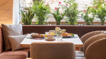 Un coin repas avec une table mise pour le petit-déjeuner, comprenant du pain, des viennoiseries et une tasse de café.