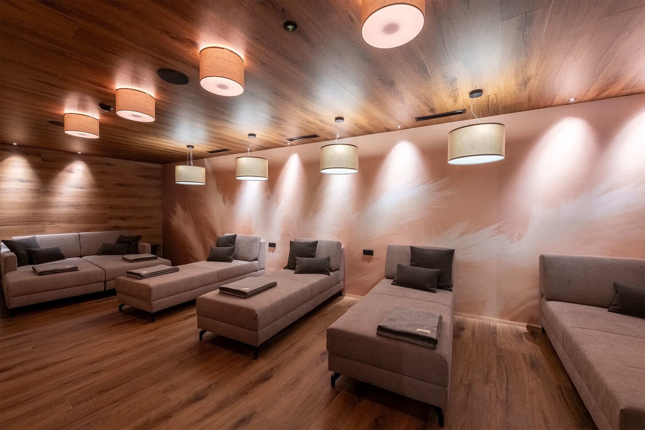 Una stanza spa con pavimento in legno, diversi divani e lampade a soffitto.