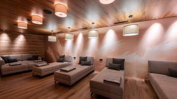 Una stanza spa con pavimento in legno, diversi divani e lampade a soffitto.